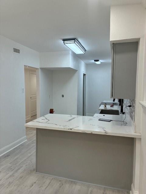 29 Snipe St, New Orleans, LA 70124 - kitchen featuring a peninsula, light stone countertops, light wood finished floors, and white cabinets