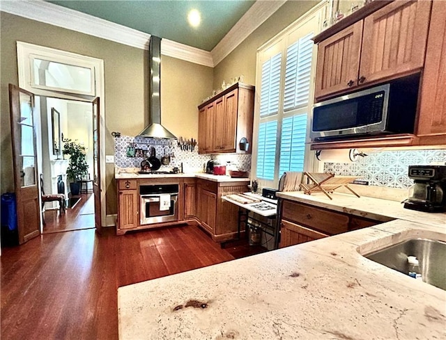 91315 Arabella St, New Orleans, LA 70115 - kitchen with stainless steel appliances, wall chimney exhaust hood, crown molding, tasteful backsplash, and brown cabinets