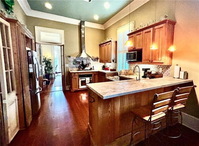 91315 Arabella St, New Orleans, LA 70115 - kitchen with stainless steel appliances, brown cabinetry, extractor fan, a peninsula, and light countertops