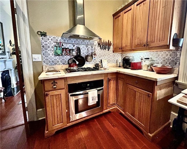 91315 Arabella St, New Orleans, LA 70115 - kitchen with wall chimney range hood, appliances with stainless steel finishes, brown cabinets, and dark wood finished floors