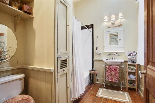 91315 Arabella St, New Orleans, LA 70115 - bathroom featuring a wainscoted wall, wood finished floors, and shower / tub combo