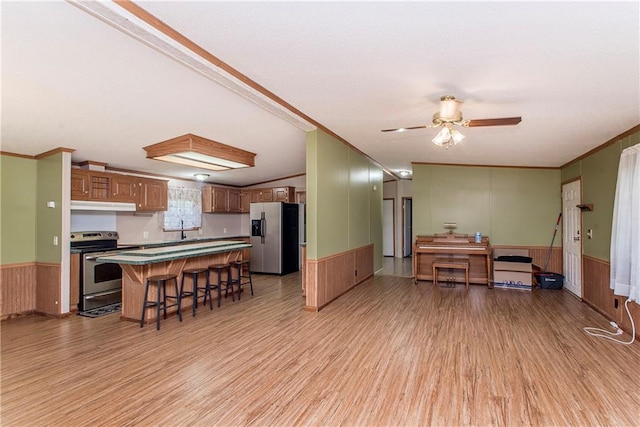 25169 Stepp Rd, Robert, LA 70455 - kitchen with stainless steel appliances, light wood-style flooring, under cabinet range hood, wainscoting, and crown molding