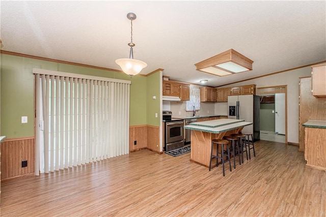 25169 Stepp Rd, Robert, LA 70455 - kitchen featuring stainless steel appliances, light wood-type flooring, a wainscoted wall, a kitchen island, and a kitchen bar