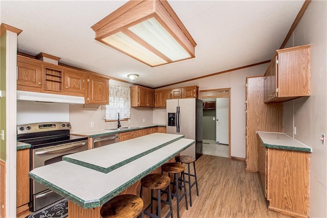 25169 Stepp Rd, Robert, LA 70455 - kitchen featuring under cabinet range hood, appliances with stainless steel finishes, lofted ceiling, a breakfast bar, and a center island
