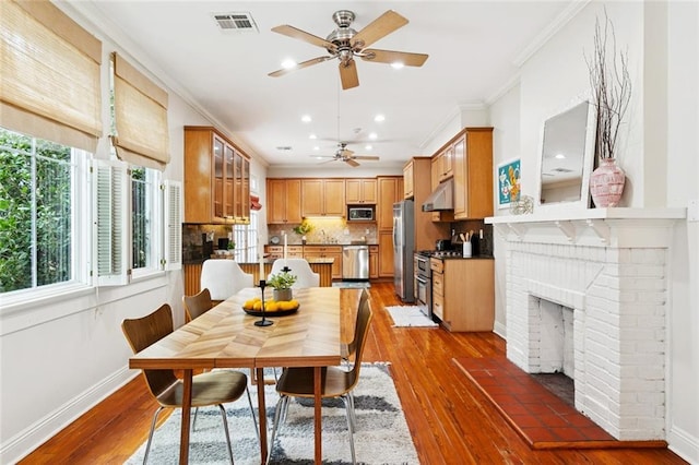 1906 Audubon St, New Orleans, LA 70118 - dining space featuring ornamental molding, ceiling fan, light wood-style floors, a fireplace, and recessed lighting