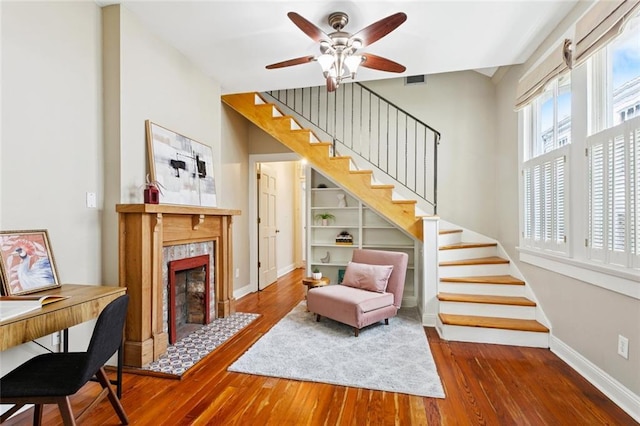1906 Audubon St, New Orleans, LA 70118 - living room featuring wood-type flooring, stairs, a tile fireplace, and ceiling fan