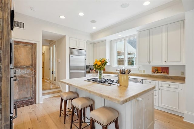 450 Fairway Dr, New Orleans, LA 70124 - kitchen featuring stainless steel appliances, a breakfast bar area, ornamental molding, light wood-style floors, and white cabinetry