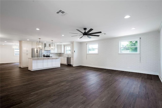 5613 Morton St, Metairie, LA 70003 - unfurnished living room with brick wall, dark wood finished floors, recessed lighting, a chandelier, and a ceiling fan