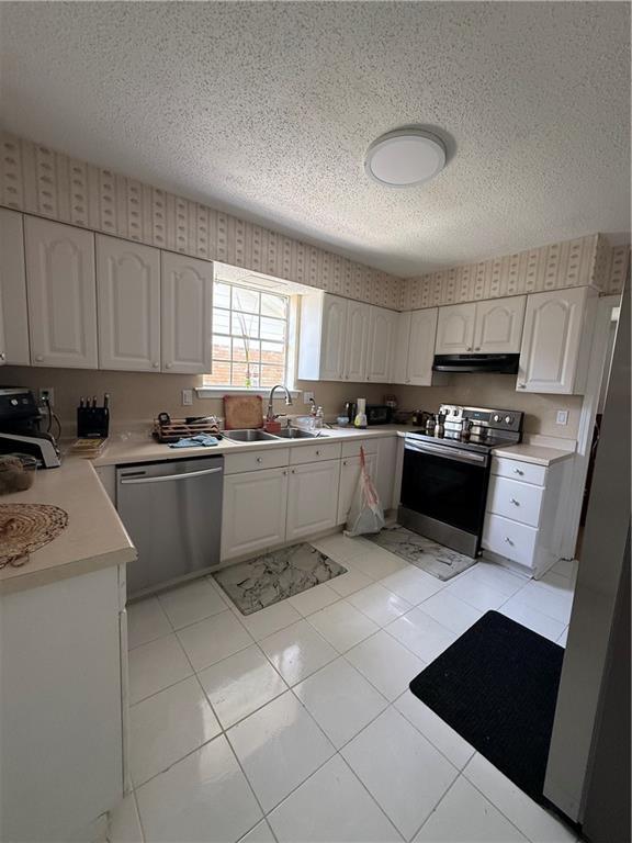3757 Mimosa Ct, New Orleans, LA 70131 - kitchen with stainless steel appliances, under cabinet range hood, a textured ceiling, light countertops, and white cabinetry