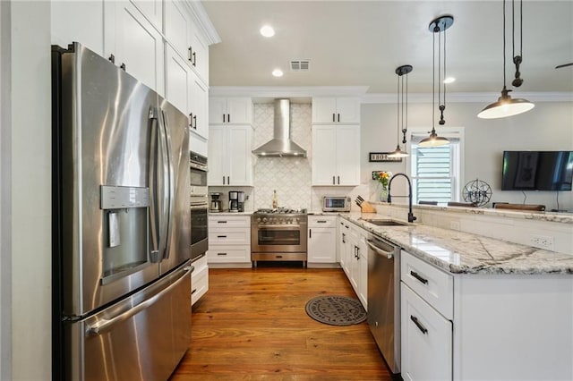 819 Franklin Ave, New Orleans, LA 70117 - kitchen with appliances with stainless steel finishes, wall chimney range hood, ornamental molding, a peninsula, and backsplash
