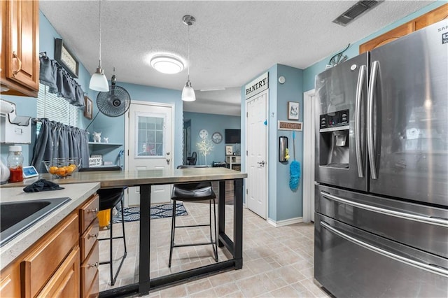 1799 Kings Row, Slidell, LA 70461 - kitchen featuring stainless steel refrigerator with ice dispenser, brown cabinetry, hanging light fixtures, light countertops, and a textured ceiling