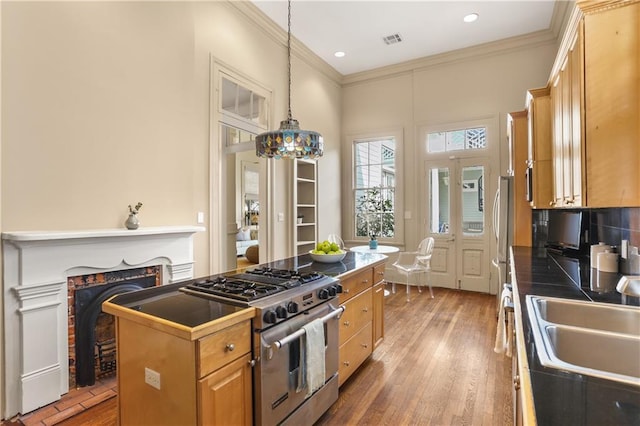 3325 Coliseum St, New Orleans, LA 70115 - kitchen with high end stove, crown molding, light wood finished floors, decorative light fixtures, and recessed lighting