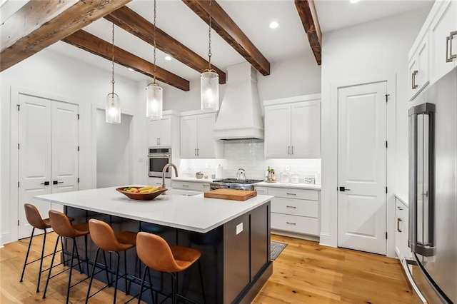 1185 Delta Ln, Covington, LA 70433 - kitchen featuring stainless steel appliances, premium range hood, backsplash, a kitchen breakfast bar, and an island with sink