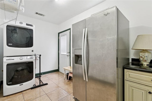 2517 Myrtle St, New Orleans, LA 70122 - kitchen featuring stainless steel fridge with ice dispenser, stacked washer and clothes dryer, cream cabinets, dark countertops, and light tile patterned floors