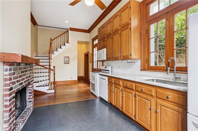 1124 Barracks St, New Orleans, LA 70116 - kitchen with white appliances, ornamental molding, ceiling fan, brown cabinetry, and a fireplace