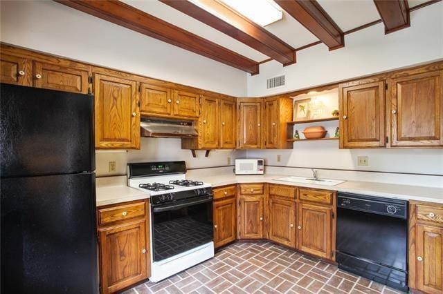 1124 Barracks St, New Orleans, LA 70116 - kitchen with black appliances, under cabinet range hood, brick patterned floors, and light countertops