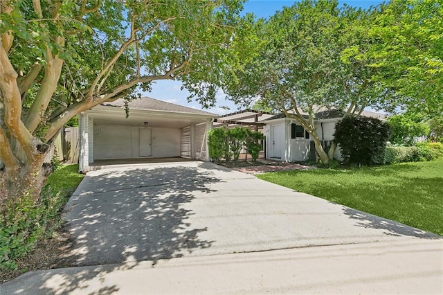 4400 Cleveland Pl, Metairie, LA 70003 - view of front of house featuring driveway, a carport, a front lawn, and an outbuilding