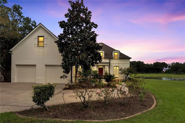 15 Muirfield Pl, New Orleans, LA 70131 - view of front of property featuring an attached garage, driveway, a front yard, stucco siding, and a water view
