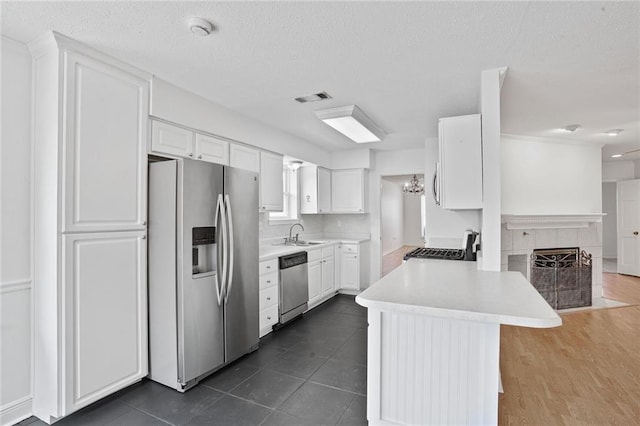 4152 Cognac Dr, Kenner, LA 70065 - kitchen featuring appliances with stainless steel finishes, white cabinetry, light countertops, a peninsula, and a textured ceiling
