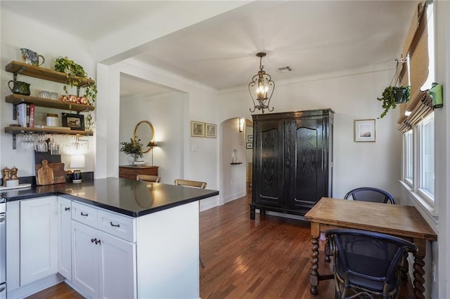 4717 Orleans Blvd, Jefferson, LA 70121 - kitchen with arched walkways, dark countertops, dark wood-type flooring, white cabinetry, and open shelves