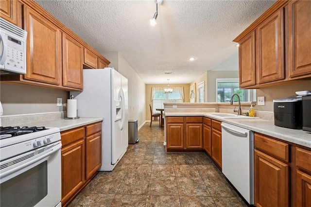 1702 Barrymore St, Slidell, LA 70461 - kitchen with white appliances, brown cabinets, a chandelier, a peninsula, and a textured ceiling