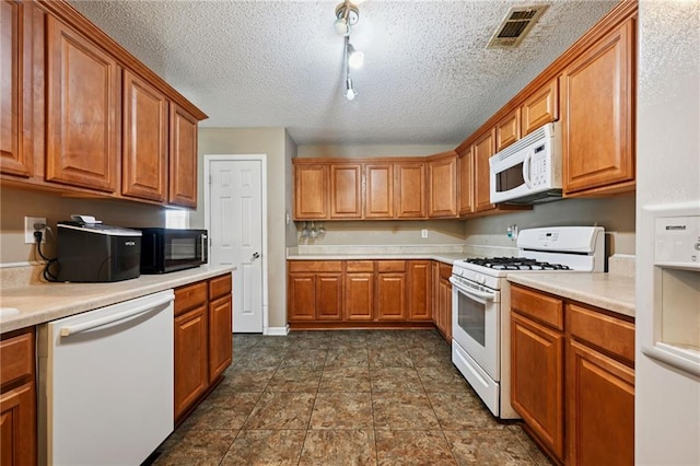 1702 Barrymore St, Slidell, LA 70461 - kitchen with white appliances, brown cabinets, light countertops, track lighting, and a textured ceiling