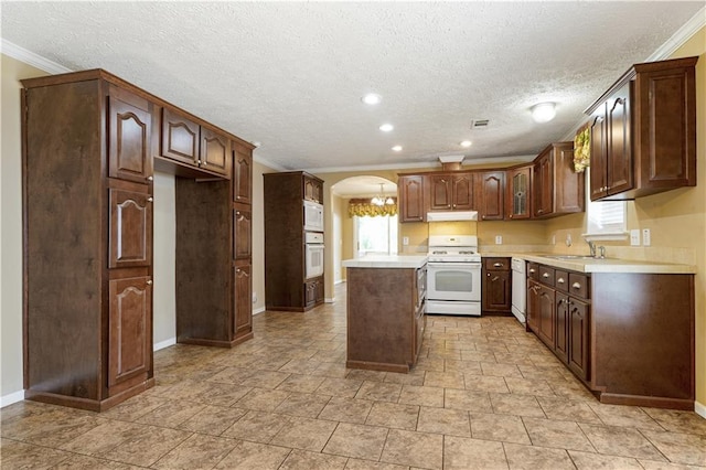 4850 Pauline Dr, New Orleans, LA 70126 - kitchen featuring white appliances, a kitchen island, under cabinet range hood, crown molding, and arched walkways