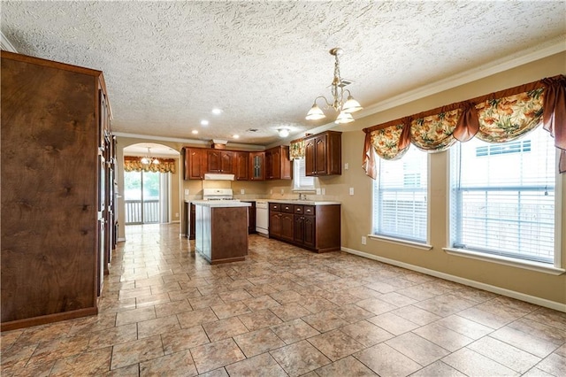 4850 Pauline Dr, New Orleans, LA 70126 - kitchen with a chandelier, arched walkways, under cabinet range hood, ornamental molding, and light countertops