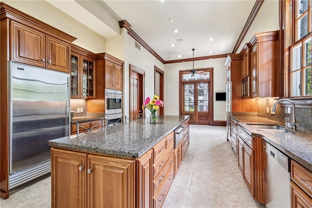 52 Tokalon Pl, Metairie, LA 70001 - kitchen featuring stainless steel appliances, a kitchen island, brown cabinetry, ornamental molding, and healthy amount of natural light
