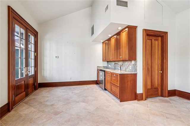 52 Tokalon Pl, Metairie, LA 70001 - kitchen with stainless steel dishwasher, high vaulted ceiling, brown cabinets, french doors, and decorative backsplash