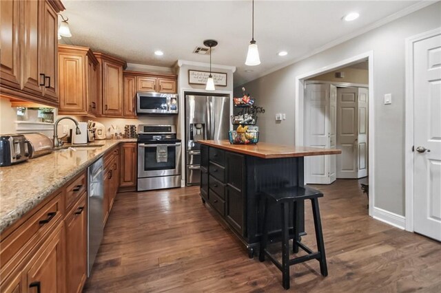 4969 Tasha Ln, Jean Lafitte, LA 70067 - kitchen featuring appliances with stainless steel finishes, brown cabinets, dark wood-style floors, hanging light fixtures, and crown molding
