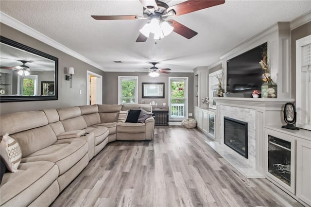 4969 Tasha Ln, Jean Lafitte, LA 70067 - living room featuring a fireplace, light wood-type flooring, a ceiling fan, crown molding, and a textured ceiling