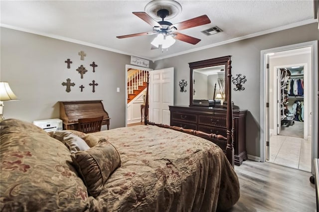 4969 Tasha Ln, Jean Lafitte, LA 70067 - bedroom featuring light wood finished floors, a ceiling fan, ornamental molding, and a walk in closet