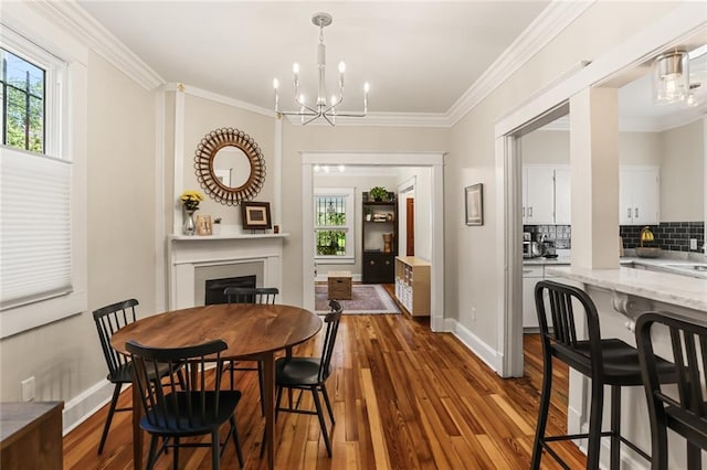 1824 Ursulines Ave, New Orleans, LA 70116 - dining room featuring healthy amount of natural light, a fireplace, dark wood-style floors, a chandelier, and ornamental molding