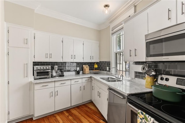 1824 Ursulines Ave, New Orleans, LA 70116 - kitchen featuring stainless steel appliances, light countertops, ornamental molding, white cabinets, and tasteful backsplash