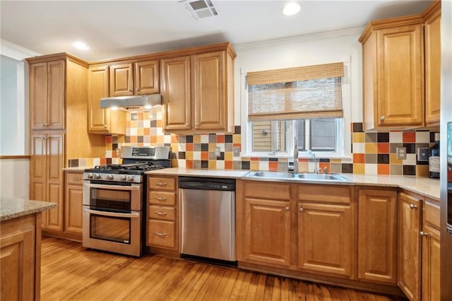 1419 Pine St, New Orleans, LA 70118 - kitchen with stainless steel appliances, under cabinet range hood, ornamental molding, light wood-style floors, and decorative backsplash