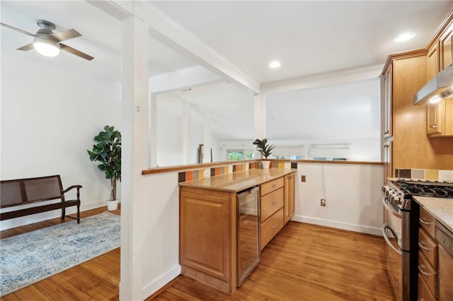 1419 Pine St, New Orleans, LA 70118 - kitchen with stainless steel gas range oven, beverage cooler, light wood-style floors, ceiling fan, and light stone counters