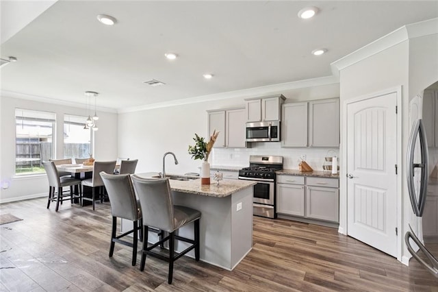 6031 Belfast Bend Ct, Slidell, LA 70461 - kitchen with appliances with stainless steel finishes, gray cabinetry, ornamental molding, an island with sink, and decorative backsplash