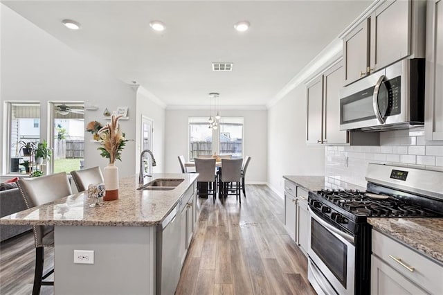 6031 Belfast Bend Ct, Slidell, LA 70461 - kitchen featuring stainless steel appliances, a kitchen bar, light wood finished floors, ornamental molding, and decorative backsplash