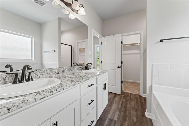 42333 Jasper Ln, Ponchatoula, LA 70454 - full bathroom featuring a spacious closet, double vanity, a garden tub, wood finished floors, and a chandelier