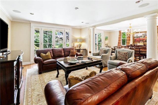 42 Crane St, New Orleans, LA 70124 - living area featuring decorative columns, plenty of natural light, light wood finished floors, and a chandelier