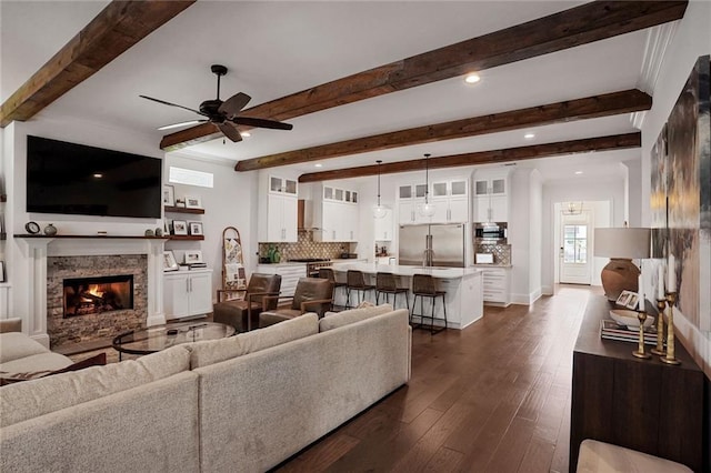 6818 Louisville St, New Orleans, LA 70124 - living room featuring a ceiling fan, beamed ceiling, dark wood-style flooring, a warm lit fireplace, and recessed lighting