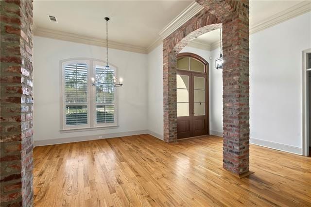 117 Grande Maison Blvd, Mandeville, LA 70471 - unfurnished dining area featuring a chandelier, ornate columns, ornamental molding, wood finished floors, and arched walkways