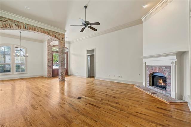 117 Grande Maison Blvd, Mandeville, LA 70471 - unfurnished living room with a fireplace, light wood-style flooring, a ceiling fan, ornamental molding, and ornate columns