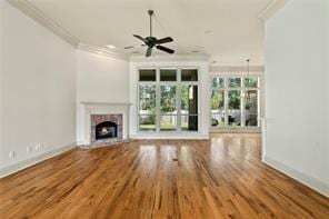117 Grande Maison Blvd, Mandeville, LA 70471 - unfurnished living room with ornamental molding, a fireplace with flush hearth, ceiling fan, and wood finished floors