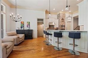117 Grande Maison Blvd, Mandeville, LA 70471 - kitchen with a chandelier, a breakfast bar area, ornamental molding, decorative light fixtures, and white cabinets