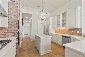 117 Grande Maison Blvd, Mandeville, LA 70471 - kitchen featuring dishwasher, a kitchen island, wall chimney range hood, decorative light fixtures, and light countertops