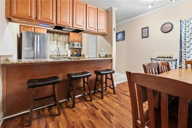 3805 Houma Blvd Unit C210, Metairie, LA 70006 - kitchen with stainless steel appliances, crown molding, wood finished floors, light stone counters, and a breakfast bar