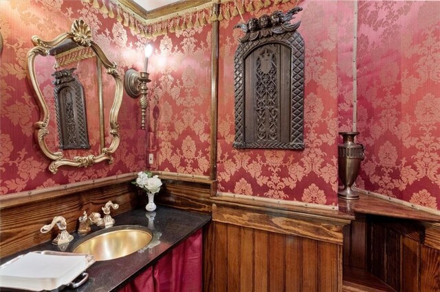 521 Dauphine St, New Orleans, LA 70112 - bathroom featuring wainscoting, vanity, and wallpapered walls