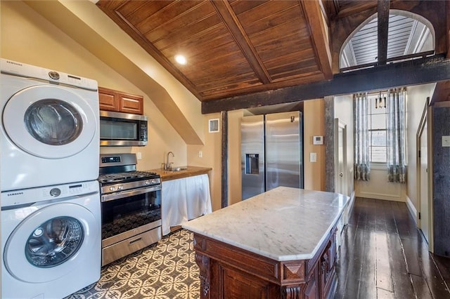 521 Dauphine St, New Orleans, LA 70112 - kitchen with stainless steel appliances, estacked washer and dryer, a wooden ceiling with exposed beams, dark wood-style flooring, and a center island